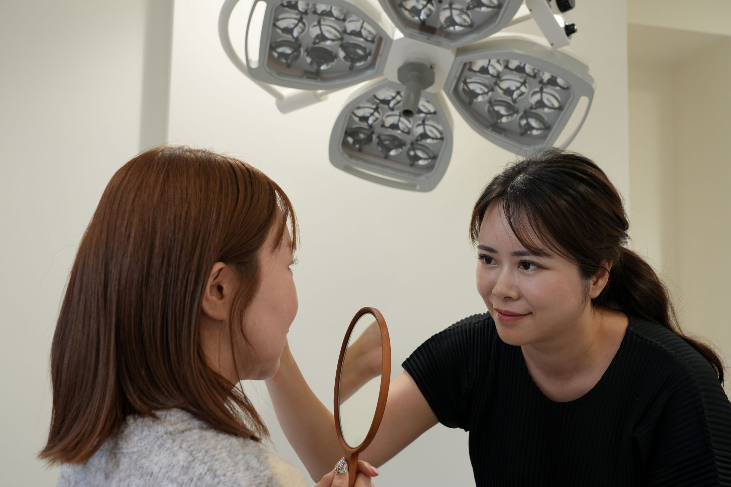 診察室で鏡を見ながら患者の肌を診察するヤヨイクリニックの女性医師